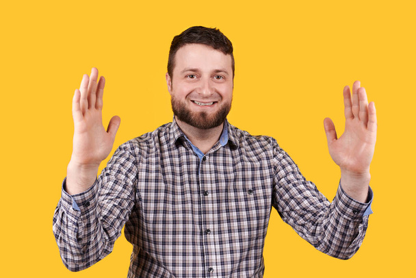 Man smiling and shoving size with hands, isolated on yellow background. - Foto, Imagem