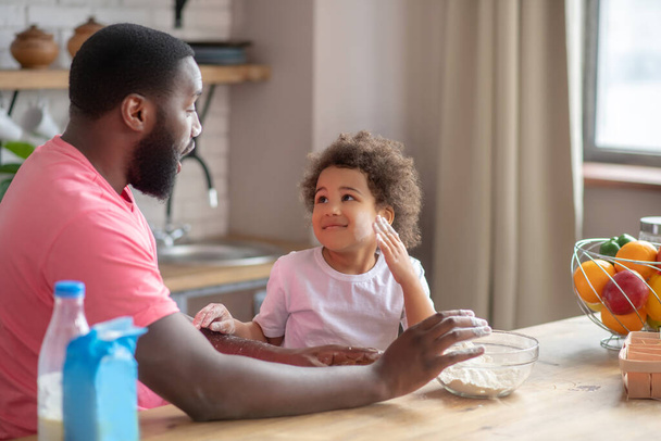 Dark-skinned father having fun with his daughter in the kitchen - Photo, Image