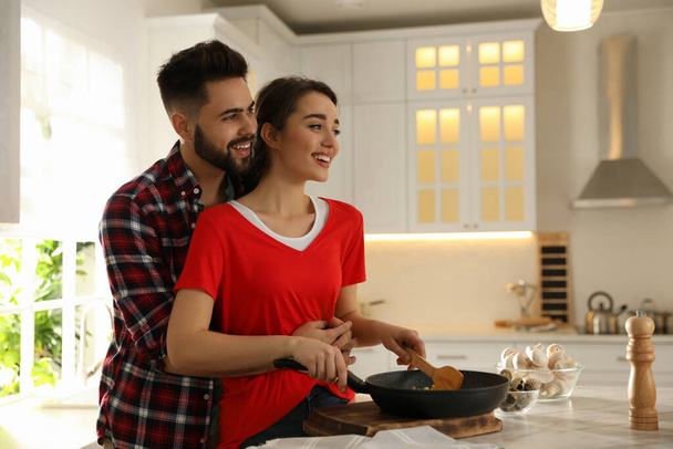 Lovely young couple cooking together in kitchen - Foto, afbeelding