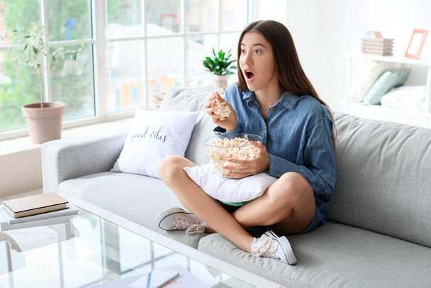 Емоційна молода жінка з попкорном дивитися фільм вдома
 - Фото, зображення