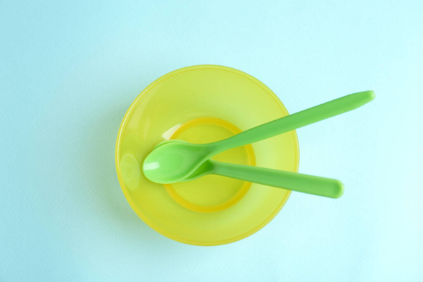 Small bowl and spoons on light blue background, top view. Serving baby food - Фото, изображение