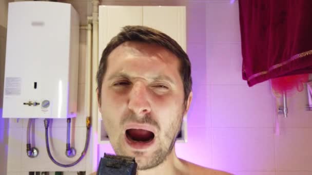Een man in de badkamer scheert, zingt en danst tegelijkertijd - Video