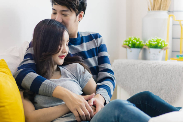 Young Asian couple hugging or embracing. Happy relationship of lover. Man kissing and holding smling woman in bedroom at home. Beautiful romantic bonding of lovely boyfriend and girlfriend. - Foto, Imagem