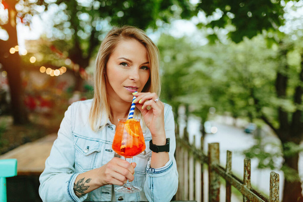 Young woman drinking Italian Cocktail - Aperol Spritz. Fine film grain texture. - Foto, Imagem