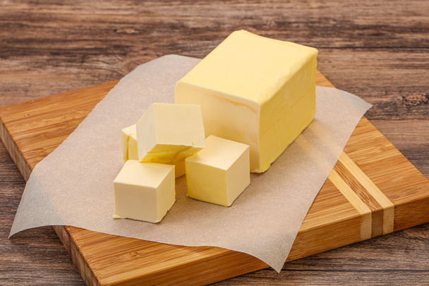 Молочний натуральний жовтий шматок масла над дошкою
 - Фото, зображення