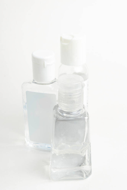 Una toma de producto de tres botellas de dispensador de plástico desinfectante de mano transparente de tamaño bolsillo genérico establecidas sobre un fondo blanco liso
. - Foto, Imagen