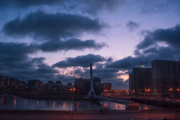 Edifícios da cidade e ponte ao entardecer, rio congelado, cidade de São Petersburgo, Federação Russa
 - Foto, Imagem