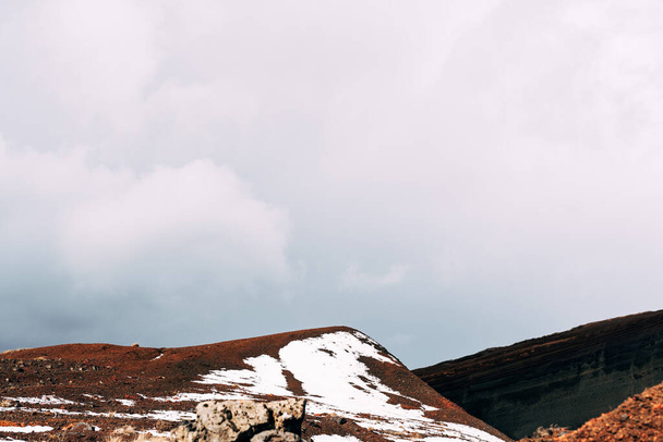 Marsjańskie krajobrazy w Islandii. Czerwony krater wulkanu Seydisholar. Kamieniołom wydobycia czerwonej ziemi. Biały śnieg leży na czerwonej ziemi. - Zdjęcie, obraz