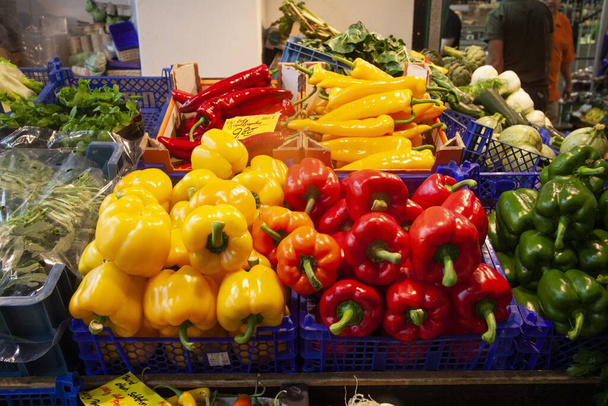 A closeup shot of colorful peppers in blue baskets on a market shelf - Fotó, kép