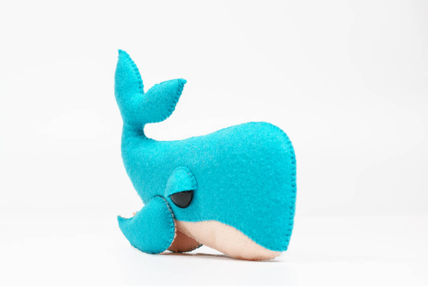 Un giocattolo di feltro sotto forma di delfino, parte di un cellulare per bambini. Su uno sfondo bianco. Cellulare per bambini colorato ed ecologico da feltro per bambini. - Foto, immagini