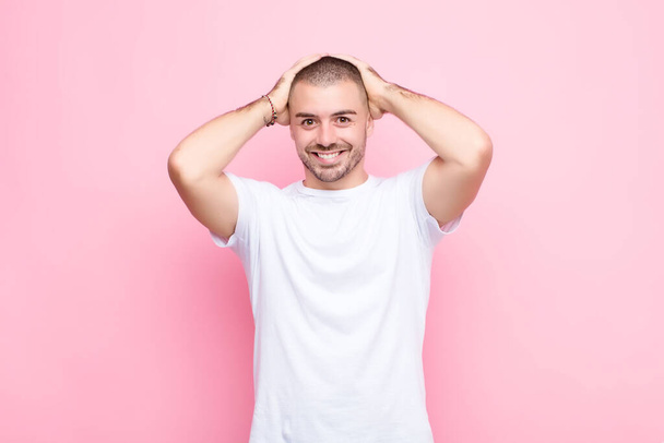 young handsome man feeling stressed, worried, anxious or scared, with hands on head, panicking at mistake against flat wall - Fotoğraf, Görsel