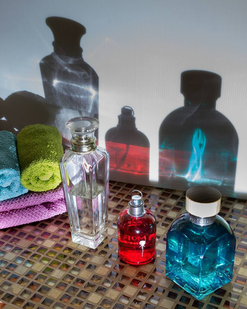A closeup shot of perfume bottles and towels with the reflection on the wall - Фото, изображение