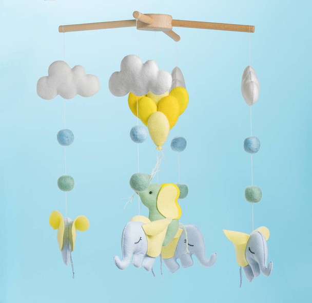 Kolorowe i ekologiczne mobilne dziecięce z filcu dla dzieci. Składa się ze słonia, chmur i balonów zabawek. Ręcznie robione na niebieskim tle. - Zdjęcie, obraz