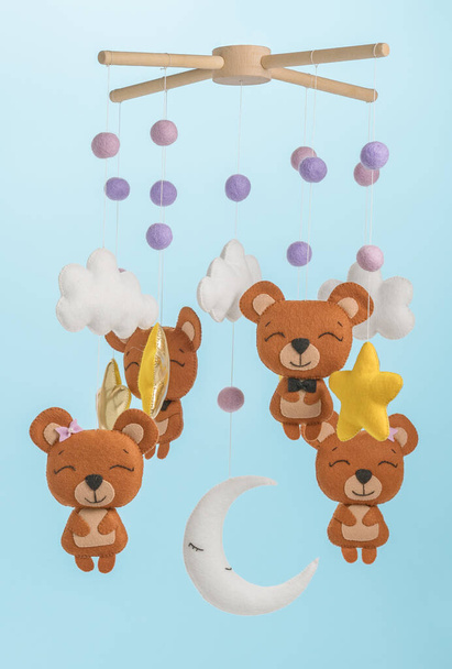 Colorful and eco-friendly children's mobile from felt for children. It consists of bears, stars,moon, clouds and balloons toys. Handmade on blue background. - Photo, Image