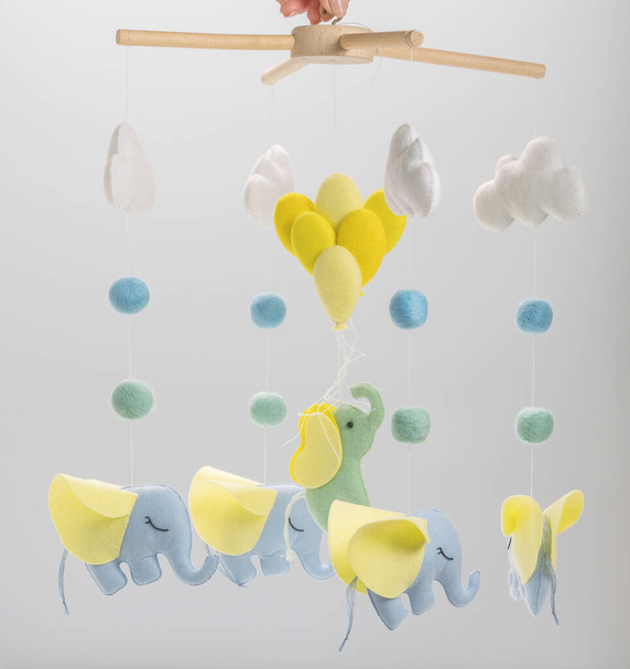 Colorful and eco-friendly children's mobile from felt for children. It consists of elephant, clouds and balloons toys. Handmade on grey background. - Photo, Image