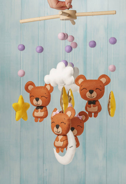 Kolorowe i ekologiczne mobilne dziecięce z filcu dla dzieci. Składa się z niedźwiedzi, gwiazd, księżyca, chmur i balonów zabawek. Ręcznie robione na niebieskim tle wykonane z drewna. - Zdjęcie, obraz