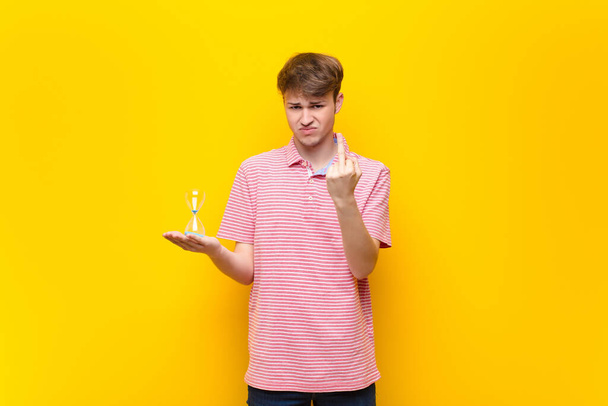 young blonde man holding a sandclock timer - Foto, afbeelding