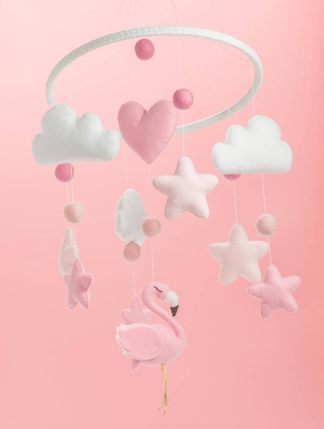 Красочный и экологичный детский мобильный телефон из войлока для детей. Он состоит из игрушек фламинго, облаков, звезд и воздушных шаров. Ручная работа на розовом фоне
. - Фото, изображение