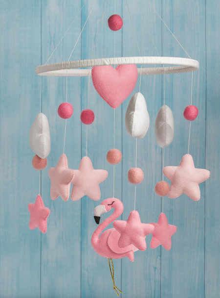 Çocuklar için yapılmış renkli ve çevre dostu bir cep telefonu. Flamingo oyuncakları, bulutlar, yıldızlar ve balonlardan oluşur. Ahşaptan yapılmış mavi arka planda el yapımı.. - Fotoğraf, Görsel