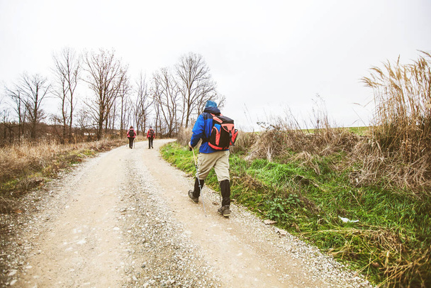 Caminhadas, Viagens, Estilo de vida saudável. Grupo de pessoas ativas com mochila andando em uma estrada rural no dia de outono. - Foto, Imagem