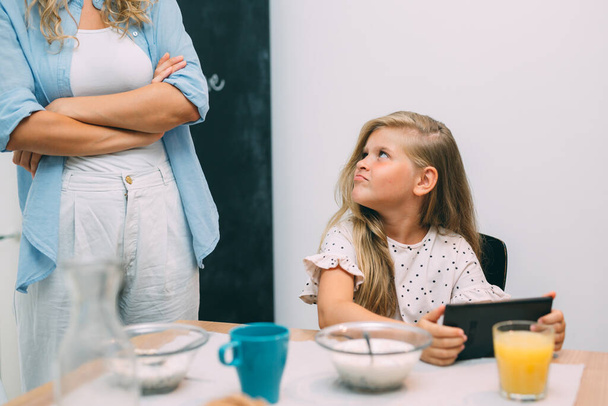 mother arguing with her daughter about using tablet computer while having breakfast - 写真・画像