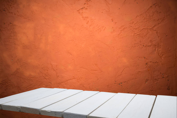 Empty wooden table on orange textured wall - Φωτογραφία, εικόνα