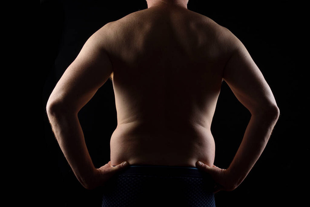 rear view of a man with hands on waist on black background - Foto, Bild