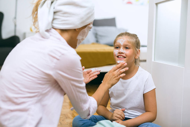 mother applying cosmetic face mask to her daughter at home - Φωτογραφία, εικόνα