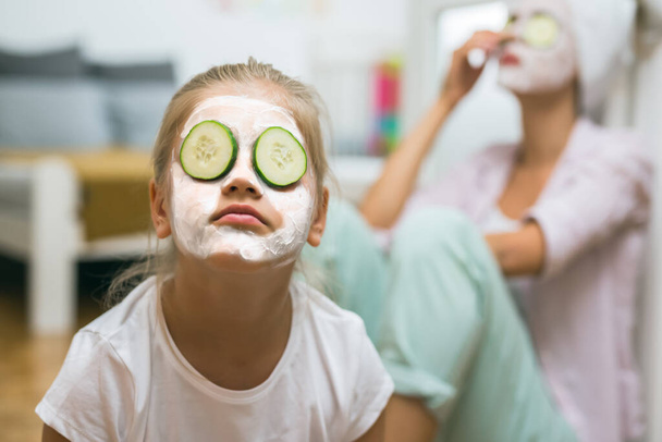 close up of girl with cosmetic face mask meditating. mother in blurred background - Foto, immagini
