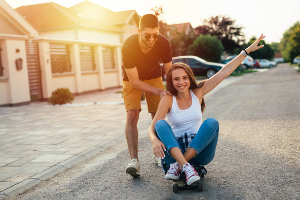 young couple having fun while driving skateboard outdoor - Foto, afbeelding