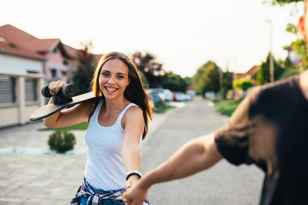 young couple having fun while driving skateboard outdoor - Фото, зображення