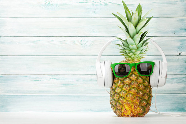 Ananas mûr avec lunettes de soleil et écouteurs. Concept de voyage et vacances. Avec espace de copie
 - Photo, image