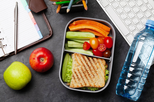 Gesunde Lunchbox mit Sandwich und Gemüse auf dem Bürotisch. Ansicht von oben. Flache Lage - Foto, Bild