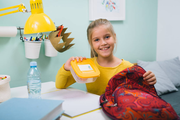 schoolgirl packing her school bag and preparing school snack - Valokuva, kuva
