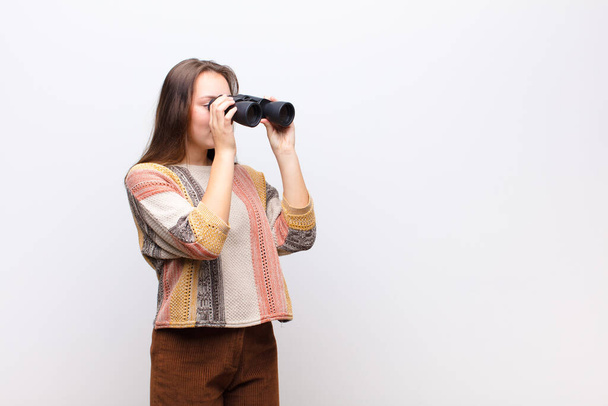 young blonde pretty girl holding a binoculars against white wall - Photo, Image