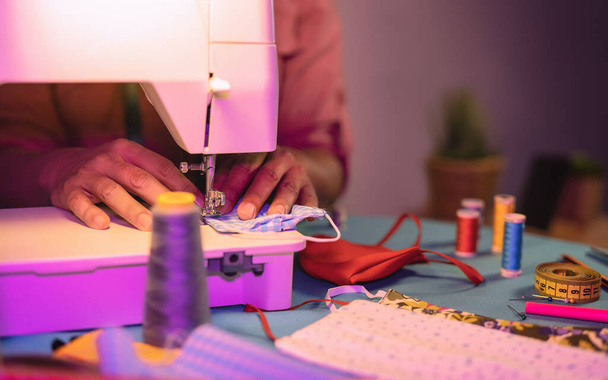 Крупним планом руки жінок-робітниць працюють з швейною машиною, роблячи обличчя медичною маскою для запобігання та припинення поширення вірусу корони концепція домашнього виробництва
 - Фото, зображення