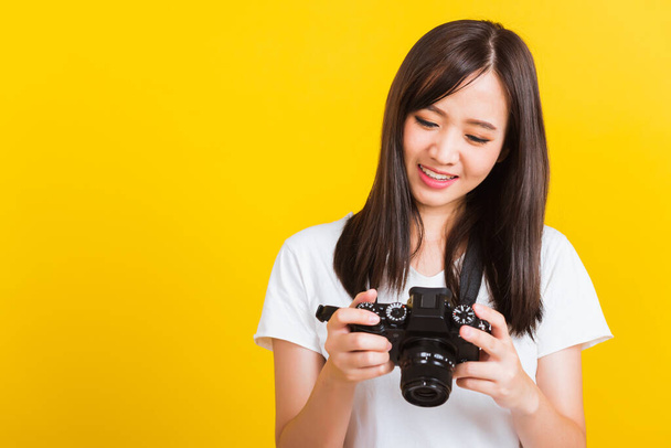 Portrait of happy Asian beautiful young woman photographer review picture she seeing a photo on the screen of digital mirrorless photo camera after photography, isolated on yellow background - Фото, зображення
