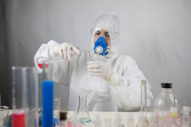 Coronavirus covid 19 infected blood vial in hand of female doctor with surgical mask and glows. Coronavirus covid 19 reseach laboratory, coronavirus covid-19 vaccine research. Selective focus - 写真・画像