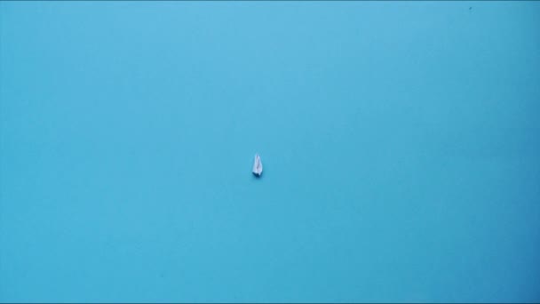 Το χάρτινο αεροπλάνο εμφανίζεται σε μπλε φόντο. Η τέχνη του να διπλώνεις πράγματα από χαρτί. Σταμάτα την κίνηση. HD βίντεο - Πλάνα, βίντεο