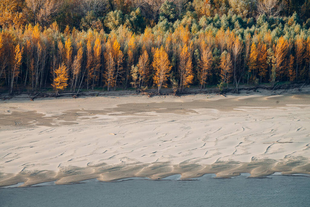 Nádherná podzimní krajina s pestrobarevným listím. Scénický břeh řeky s podzimními listy na stromech. Krajina se žlutým oranžovým listím. Krásný zlatý podzim. Barevný podzimní les. Grove near sandbank. - Fotografie, Obrázek