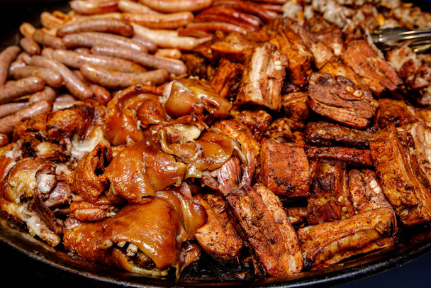 Разнообразное мясо. Сосиски на гриле, ребрышки, голень в большой сковороде
. - Фото, изображение