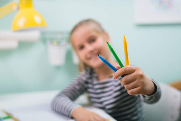 girl siting table at her room and holding felt pens - Foto, imagen