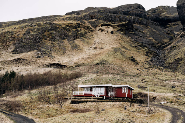 Czerwony drewniany dom u podnóża góry w Islandii. - Zdjęcie, obraz