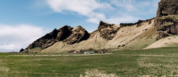 Maisons résidentielles et installations de production d'entreprises agricoles, au pied de la montagne en Islande. Prairie verte pour le pâturage
. - Photo, image