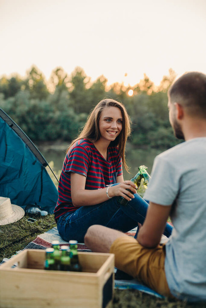 amigos bebiendo cerveza en camping al aire libre junto al río
 - Foto, Imagen