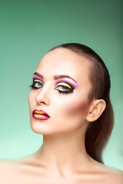 attraktive Frau mit buntem Make-up auf grünem Hintergrund - Foto, Bild