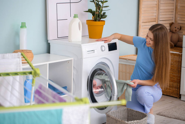 Young woman doing laundry at home - Фото, изображение