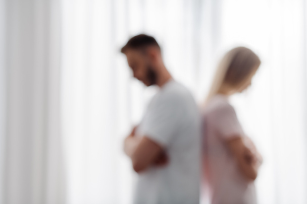 blurred view of man and woman standing with crossed arms, relationship difficulties concept  - 写真・画像