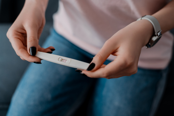 cropped view of girl holding pregnancy test with positive result  - Fotografie, Obrázek
