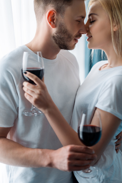 side view of cheerful man and woman holding glasses with red wine  - Fotoğraf, Görsel